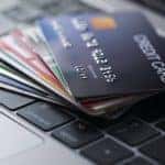 A stack of fanned out credit cards is sitting on a keyboard.