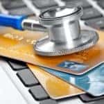 A close up is shown of a stethoscope on a stack of credit cards.
