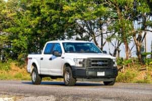 Ford F-150 driving by some trees