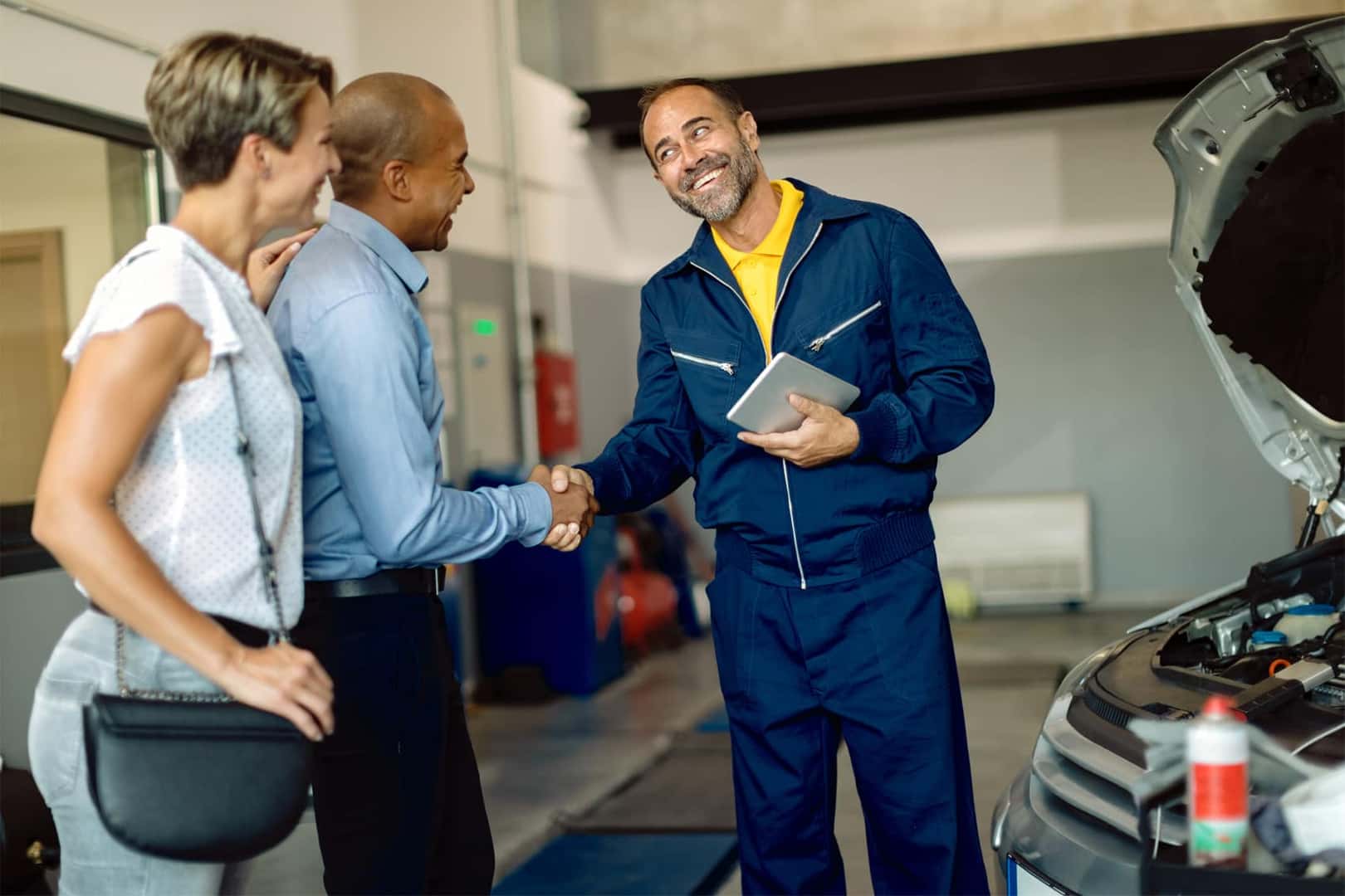 Chevrolet Certified Technician smiling while shaking hands with customer at Chevy Service Center