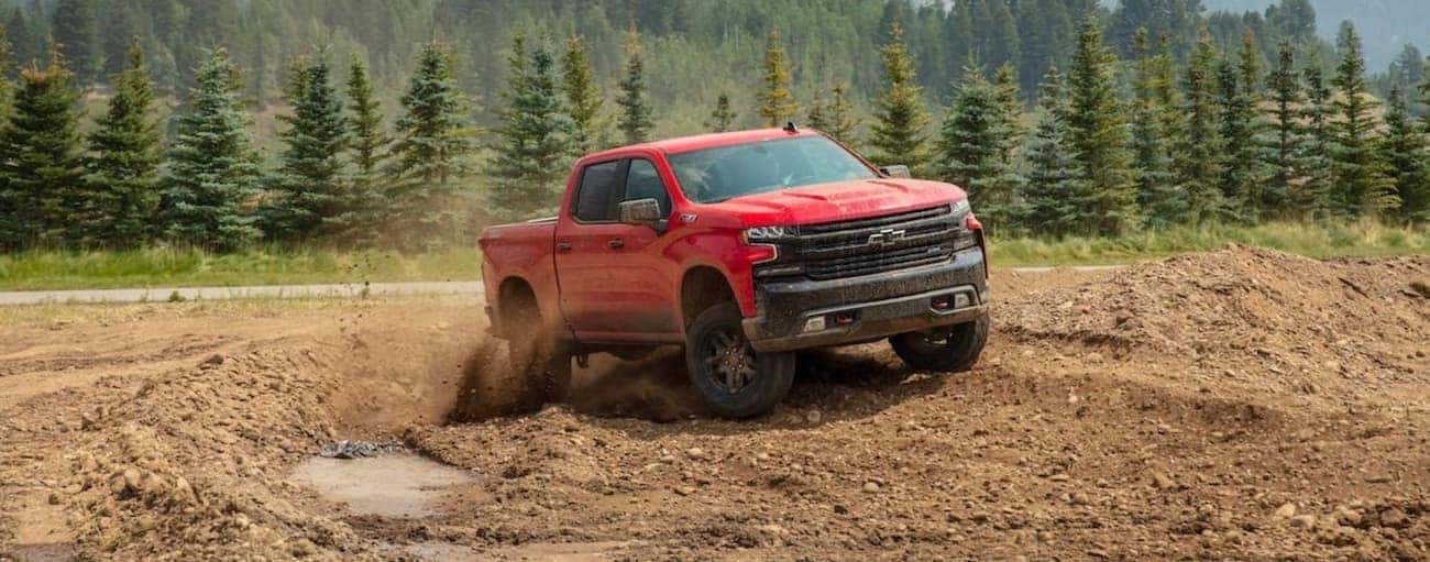 A red 2020 Chevy Silverado 1500 is off-roading in the mud.