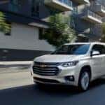 A white 2019 Chevrolet Traverse High Country is driving on a city street.