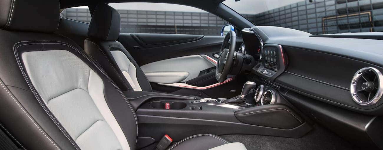 The white and black interior of a 2020 Chevy Camaro is shown with an Indianapolis building outside.