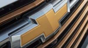 A closeup is shown of the yellow Chevrolet badge on a white 2021 Chevy Equinox.