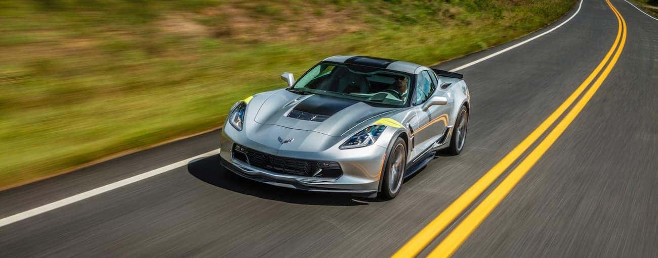 A silver 2017 used Chevrolet Corvette is driving past blurred grass.