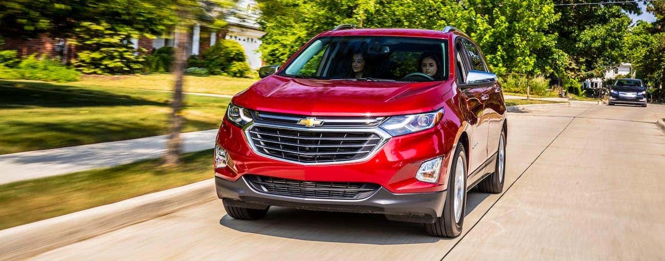 A red 2018 used Chevrolet Equinox is driving on a suburban road.