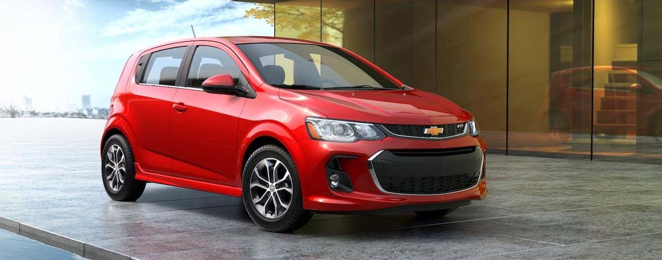 A red 2018 used Chevrolet Sonic Hatchback is parked in front of a modern home in Indianapolis, IN.