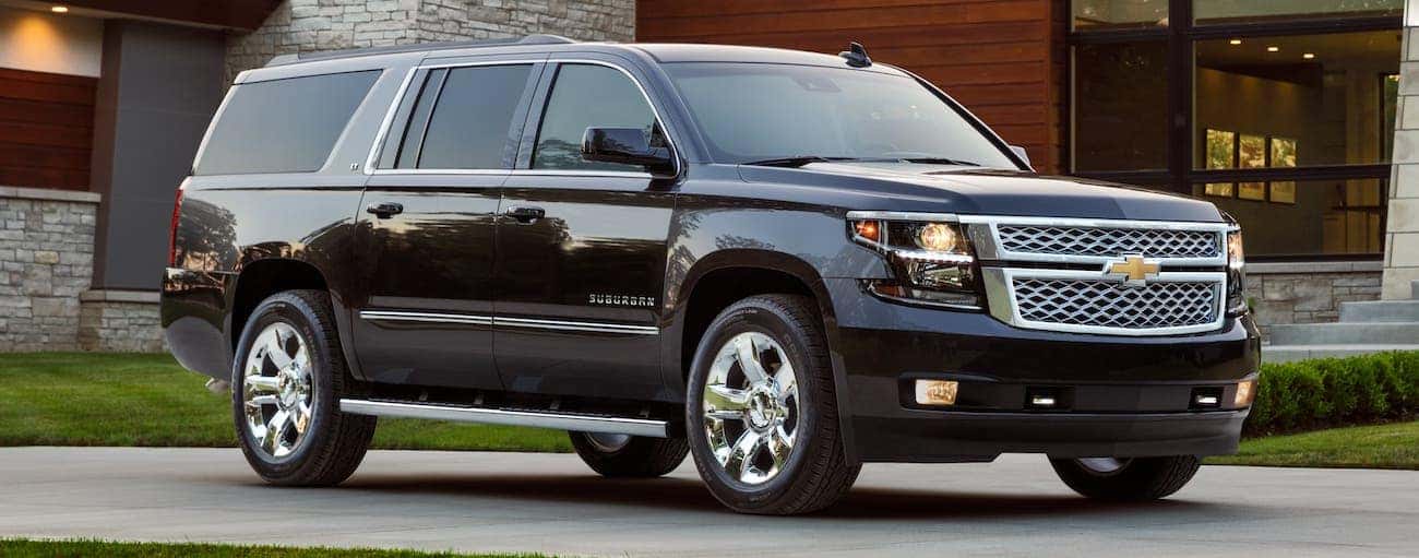 A black 2018 used Chevrolet Suburban is parked in front of a modern home outside Indianapolis, IN.