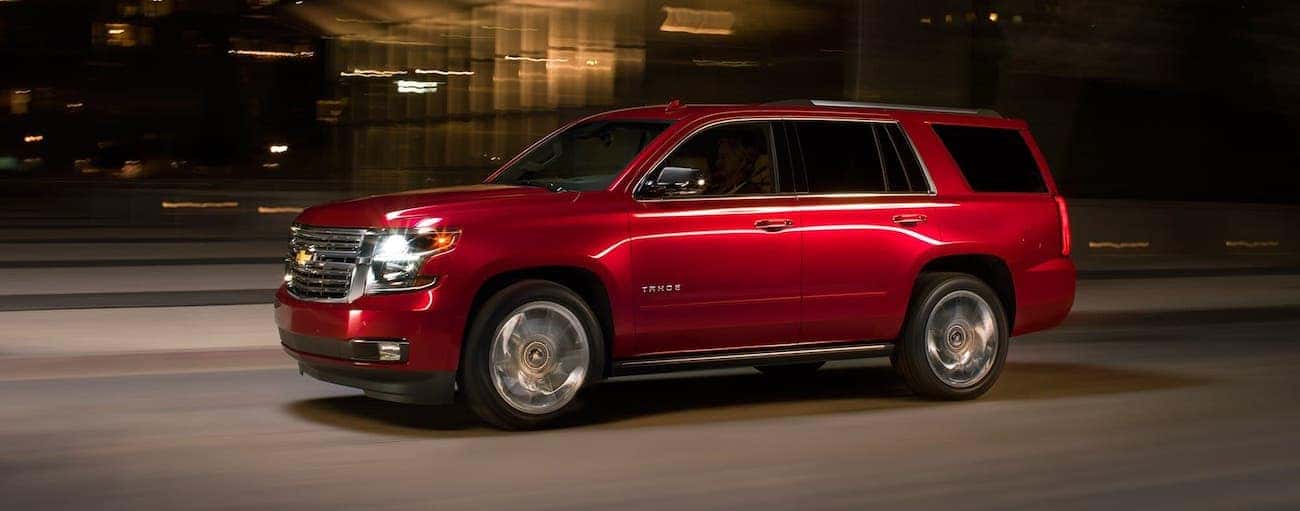 A red 2018 used Chevrolet Tahoe is driving in a city at night.
