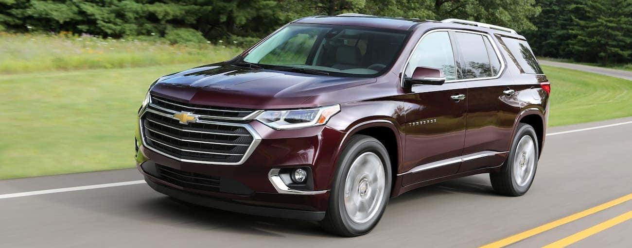 A burgundy 2018 used Chevrolet Traverse is driving on a road near Indianapolis, IN.