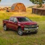 A red 2020 Chevy Silverado 1500 LTZ is parked in front of a farm, a great contender in the 2020 Chevy Silverado 1500 vs 2020 Chevy Silverado 2500HD comparison.