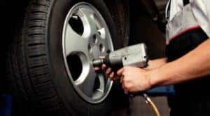 A closeup shows a mechanic's hands and an impact wrench putting a wheel on a car at a tire shop near you in Indianapolis, IN.