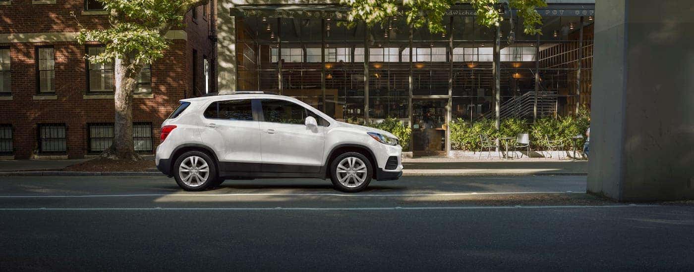A white 2021 Chevy Trax is shown from the side while parked in front of a cafe.