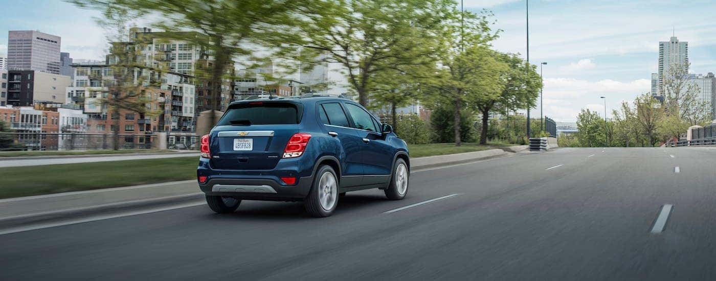 A blue 2021 Chevy Trax Premier is driving away on a highway near Indianapolis, IN.
