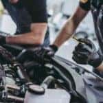 Two mechanics are checking the oil in a car as part of an oil change near you in Indianapolis.