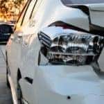 A close up is shown of of a white car that was rear ended.