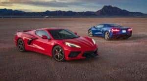 A red and a blue 2021 Chevy Corvette Stingray are parked on an empty flat in front of mountains.