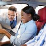 A salesman is leaning in a car with couple in it at a Chevy dealer in Indianapolis.