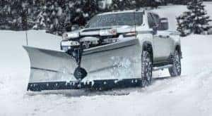 A white 2021 Chevy Silverado 2500 HD with a plow is in a snow storm.