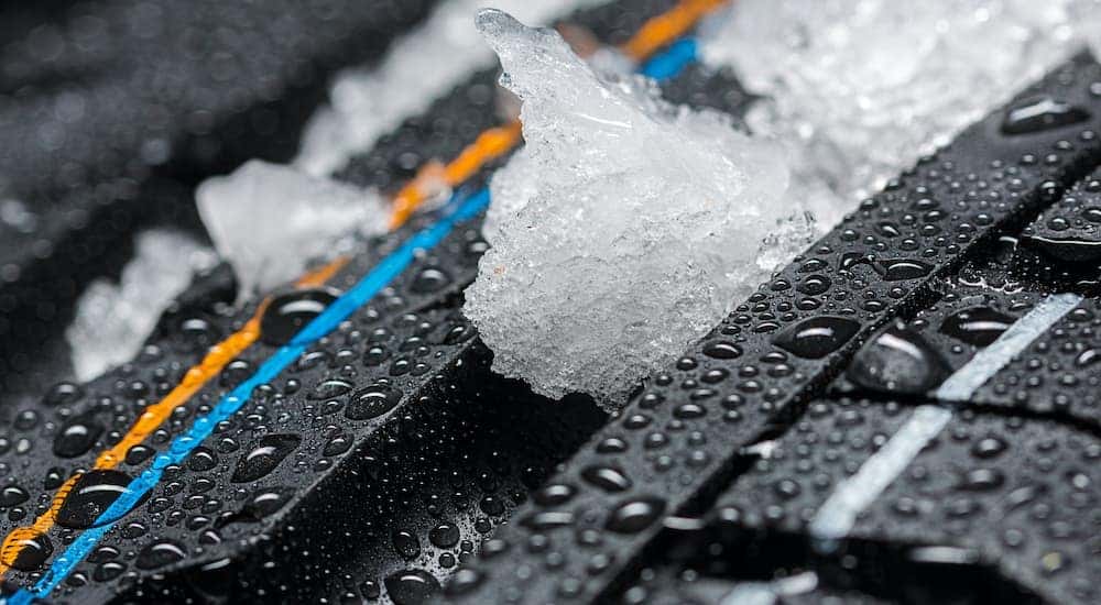 A close up shows snow in the treads of a brand new tire.