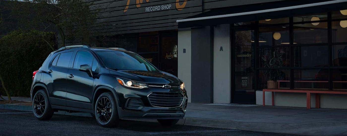 A black 2021 Chevy Trax is shown from the side while parked outside of a record shop at night 2021 Chevy Trax vs 2021 Ford EcoSport comparison.