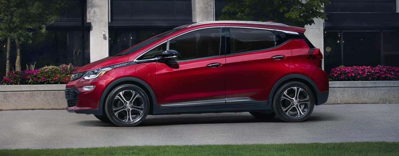 A red 2021 Chevy Bolt EV is parked in front of a black and grey building.