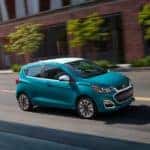 A teal 2021 Chevy Spark is shown driving through the city after leaving a Chevy dealership in Indianapolis.