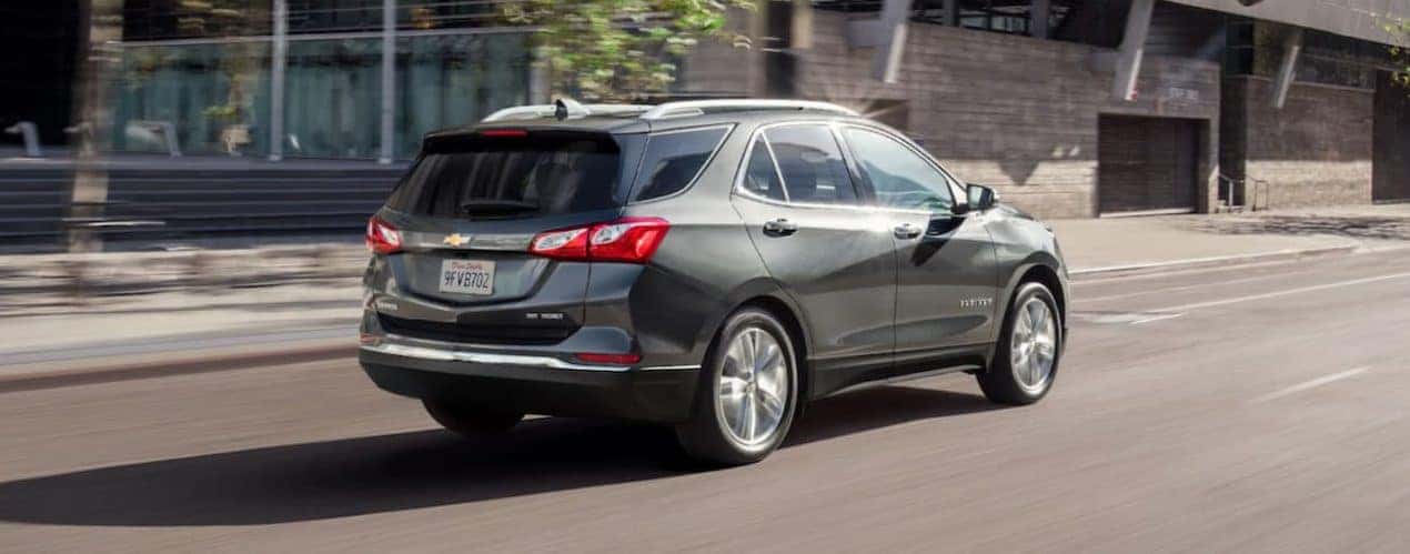 A grey 2021 Chevy Equinox is driving on a city street after winning the 2021 Chevy Equinox vs 2021 Toyota RAV4 comparison.