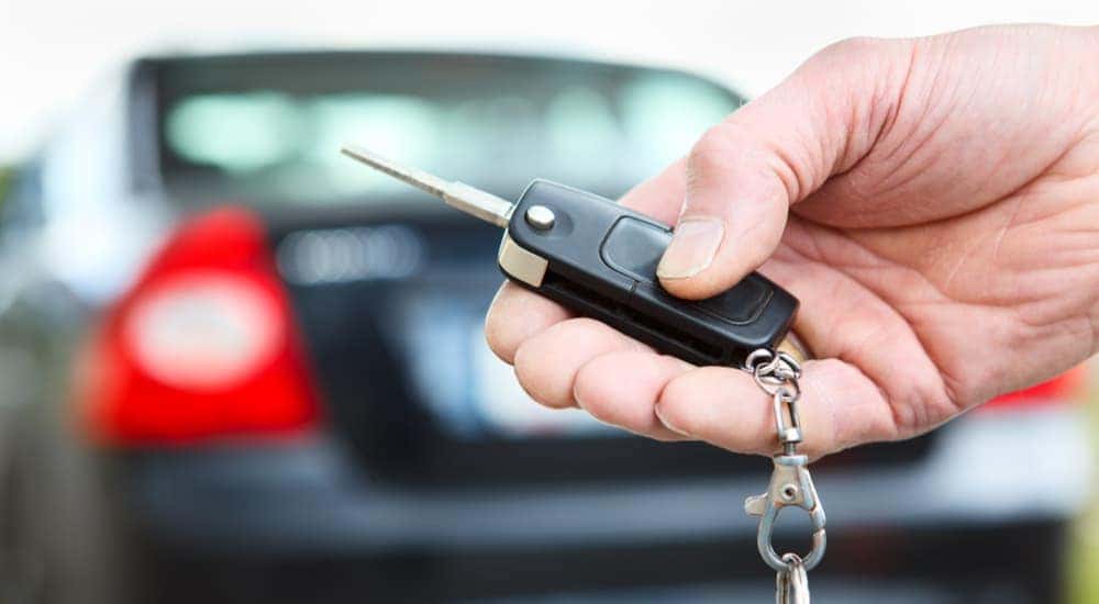 A close up shows a hand using a keyfob at a Indianapolis used car dealer.