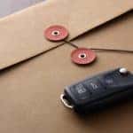 A black car key is shown resting on top of a closed envelope.