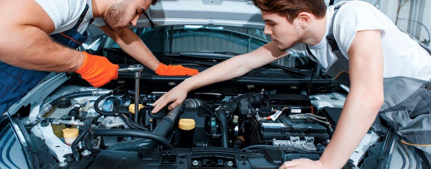 Two technicians are shown working on a vehicle at a Avon Chevrolet dealer.