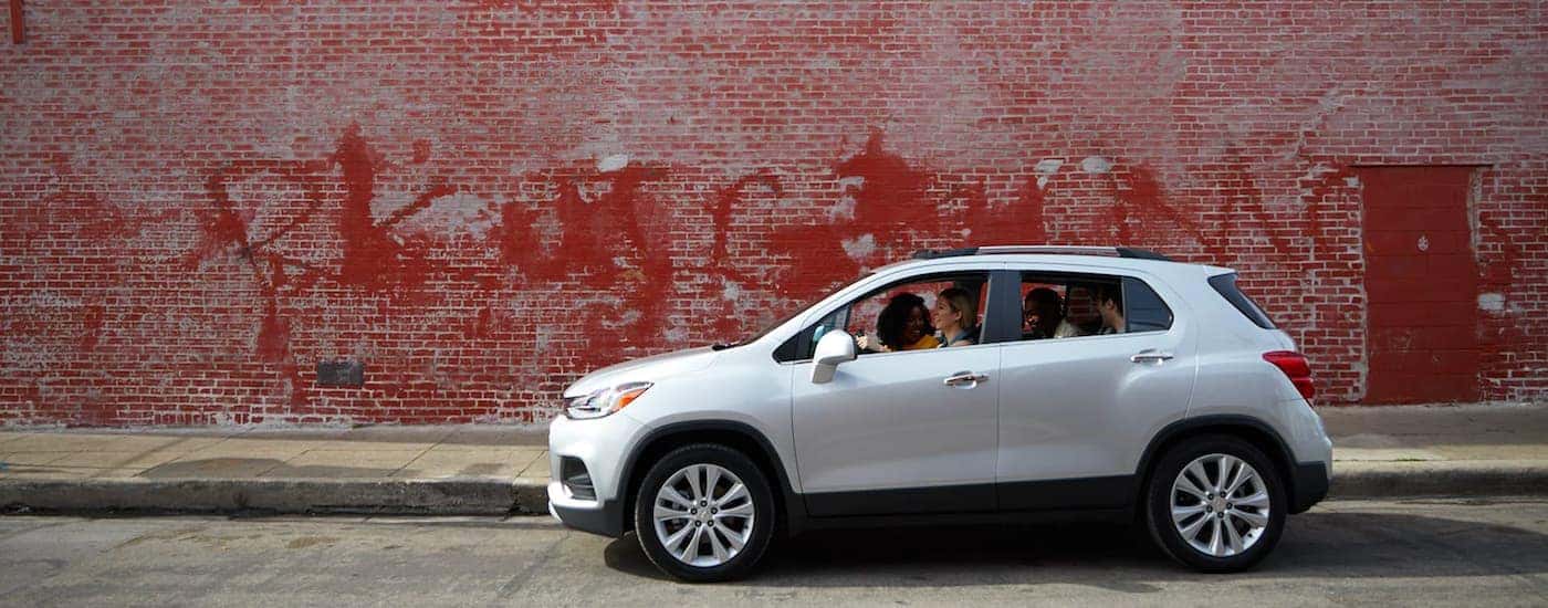A silver 2019 Chevy Trax is shown in front of a red brick wall after leaving a Carmel Chevrolet dealership.