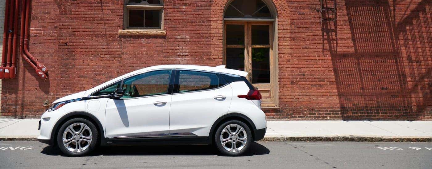 A white 2020 Chevy Bolt EV is shown from the side parked in front of a brick wall.