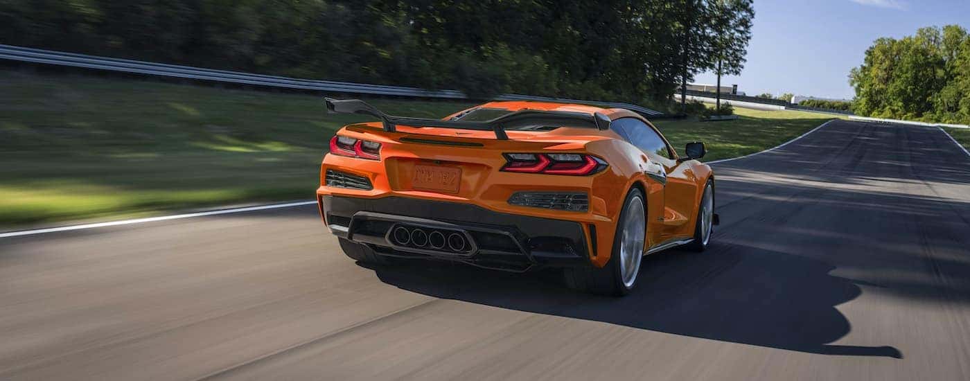 An orange 2023 Chevy Corvette Z06 is shown from the rear on a racetrack after leaving a Plainfield Chevy dealership.
