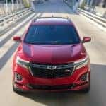 A red 2022 Chevy Equinox RS is shown from the front driving on a bridge after visiting a Chevy Equinox dealer.
