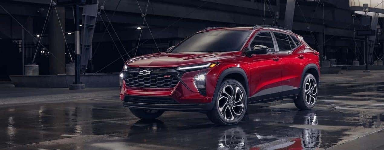 A red 2024 Chevy Trax RS is shown parked on a city street.
