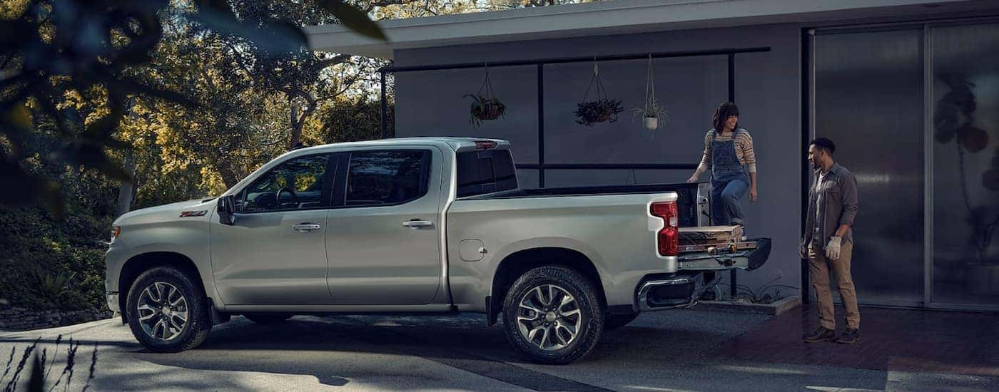 A woman and man load lumber into the bed of a silver 2022 Chevy Silverado 1500 Z71