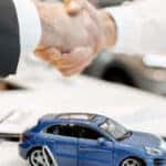 Close-up of a handshake at the table with toy car and keys