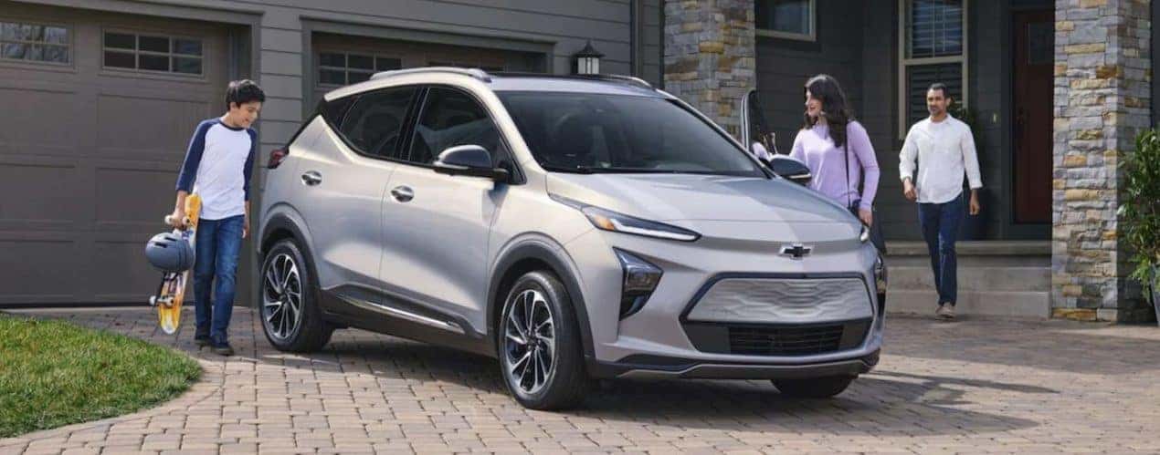 A silver 2023 Chevy Bolt EUV is shown parked in front of a house.