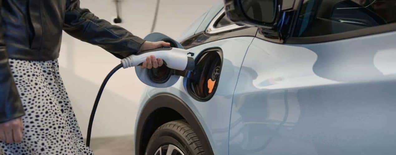 A person is shown plugging in a 2023 Chevy Bolt EV.