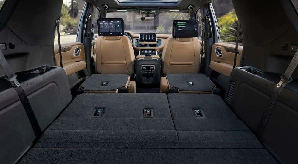 The interior of a 2021 Chevy Suburban Z71 with seats folded down and entertainment screens on the front seatbacks