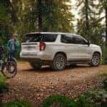 A white 2022 Chevy Tahoe Z71 parked in the woods with bicyclists nearby
