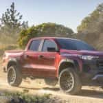 A red 2023 Chevy Colorado Trail Boss is shown from the front at an angle after leaving a dealer that has a Chevy Colorado for sale..