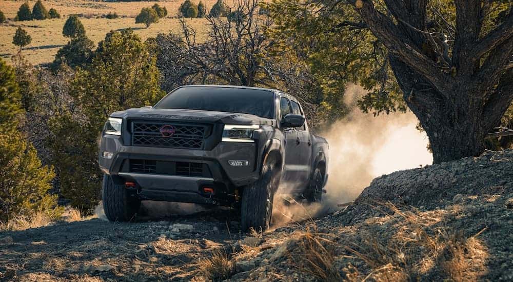 A grey 2023 Nissan Frontier Pro-4x is shown from the front while driving up a hill.