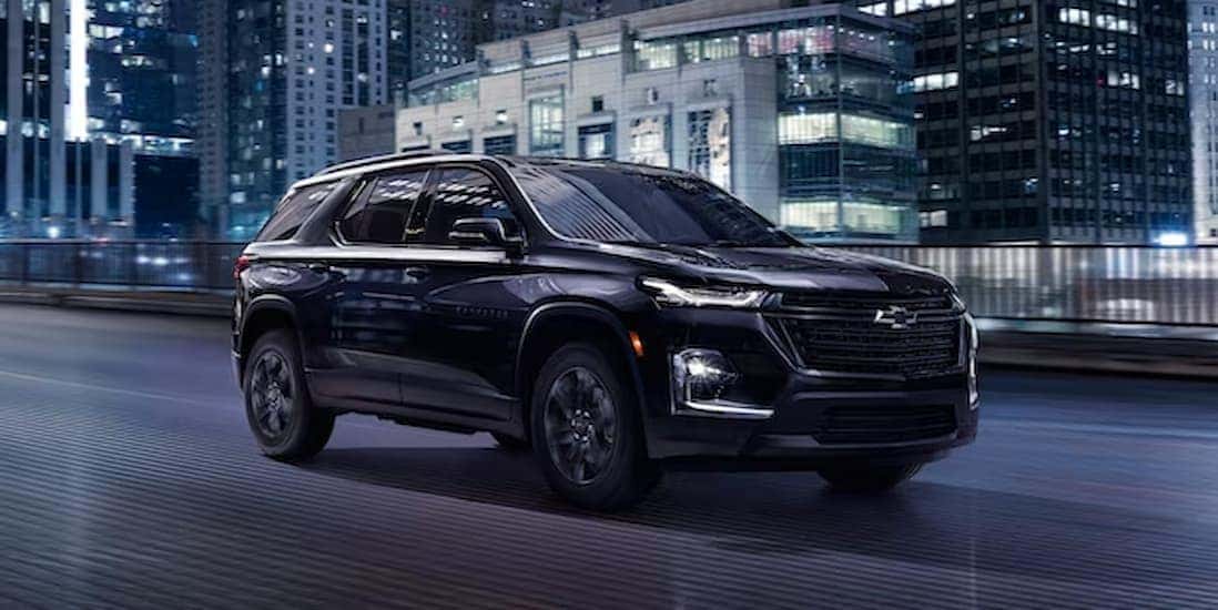 A black 2023 Chevy Traverse is shown driving on a road.