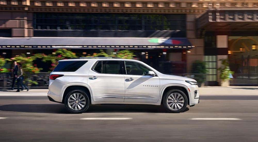 A white 2023 Chevy Traverse is shown from the side on a city street.