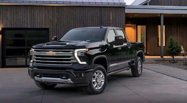 A popular Chevy Silverado for sale in Indianapolis, a black 2024 Chevy Silverado 1500 HD High Country, is shown parked on a driveway.