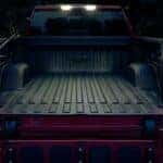 The bed and tailgate of a red 2024 Chevy Silverado 1500 is shown near a Chevy Silverado for sale near Carmel, IN.