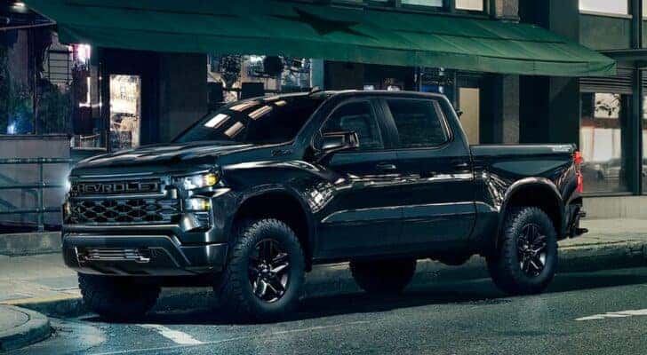 A black 2023 Chevy Silverado 1500 Z71 Trail Boss is shown from the side on a city street after leaving a dealer that has a Chevy Silverado for sale near Greenfield, IN.