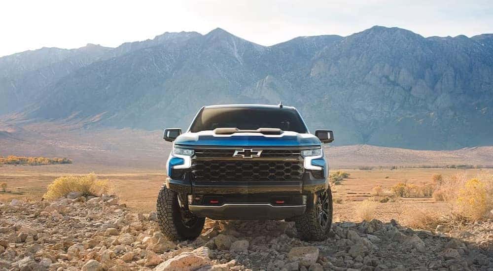 A blue 2024 Chevy Silverado 1500 ZR2 is shown parked on rocks after viewing a Chevy Silverado for Sale Near Greenfield, IN.